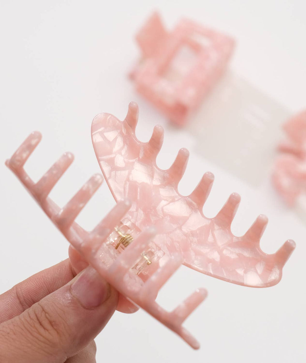 Pink clip held by a hand with a blurred background