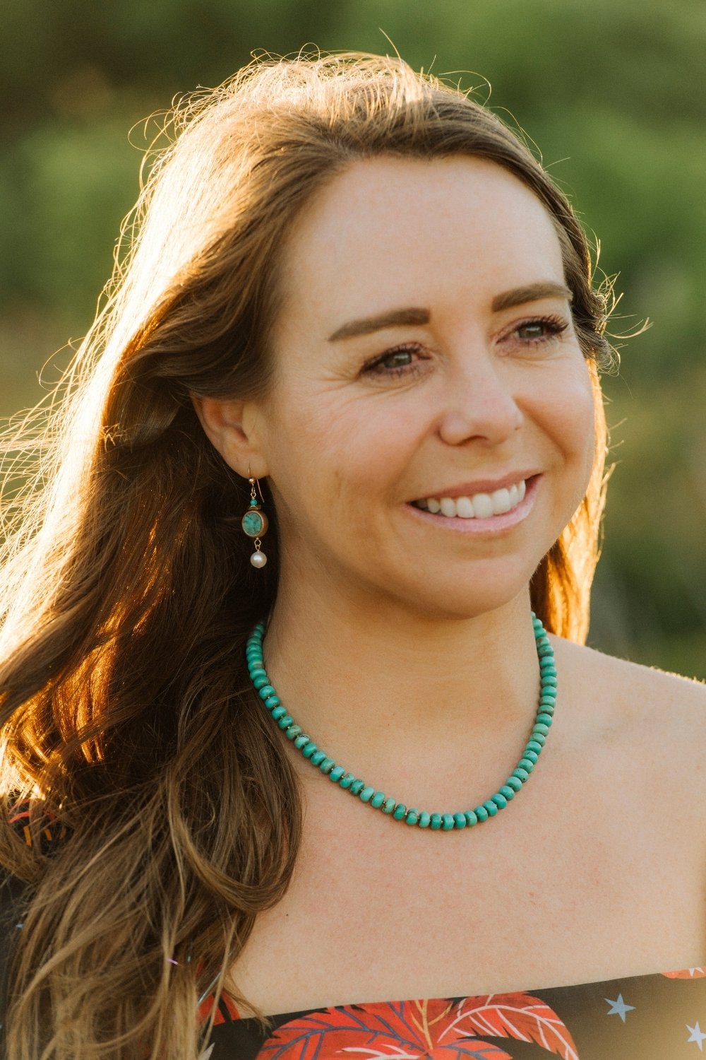 Woman wearing a Bora Bora turquoise necklace with a blurred green background