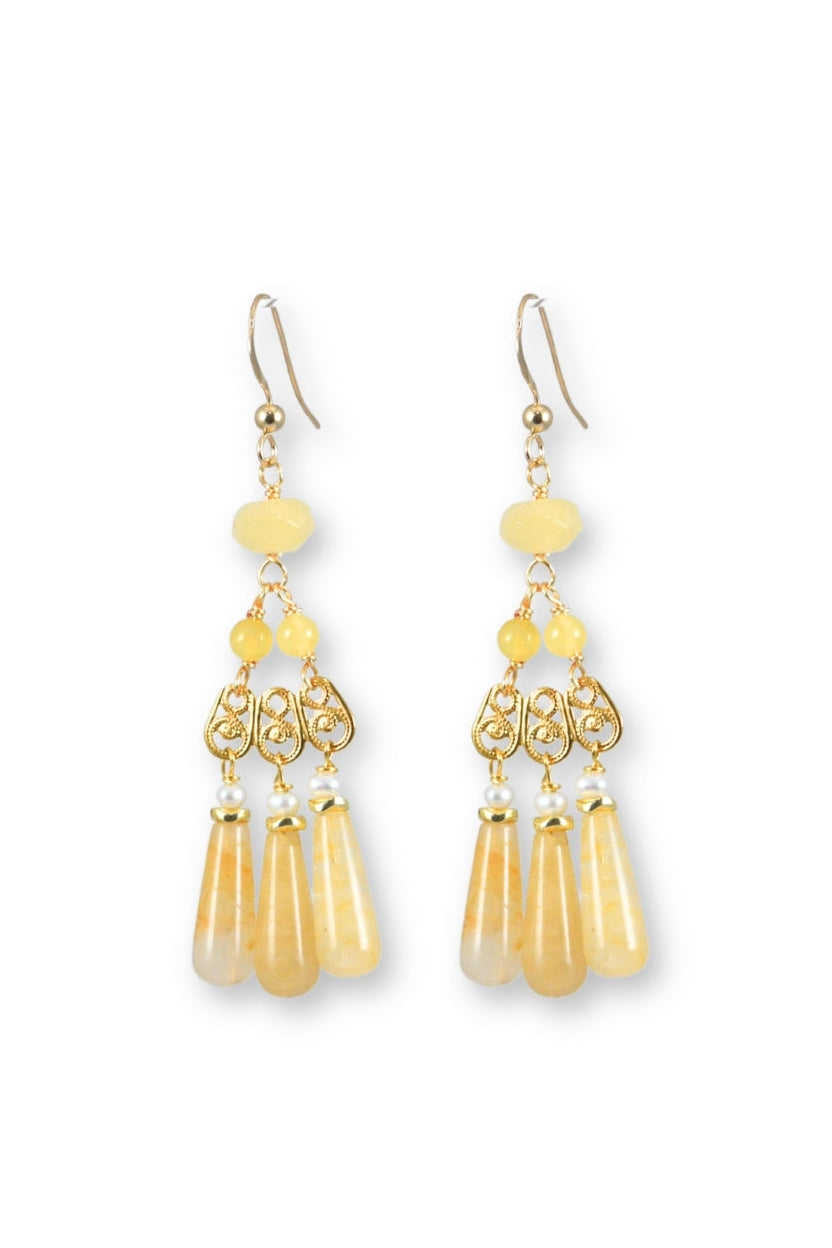 Gold earrings with yellow beads on a white background