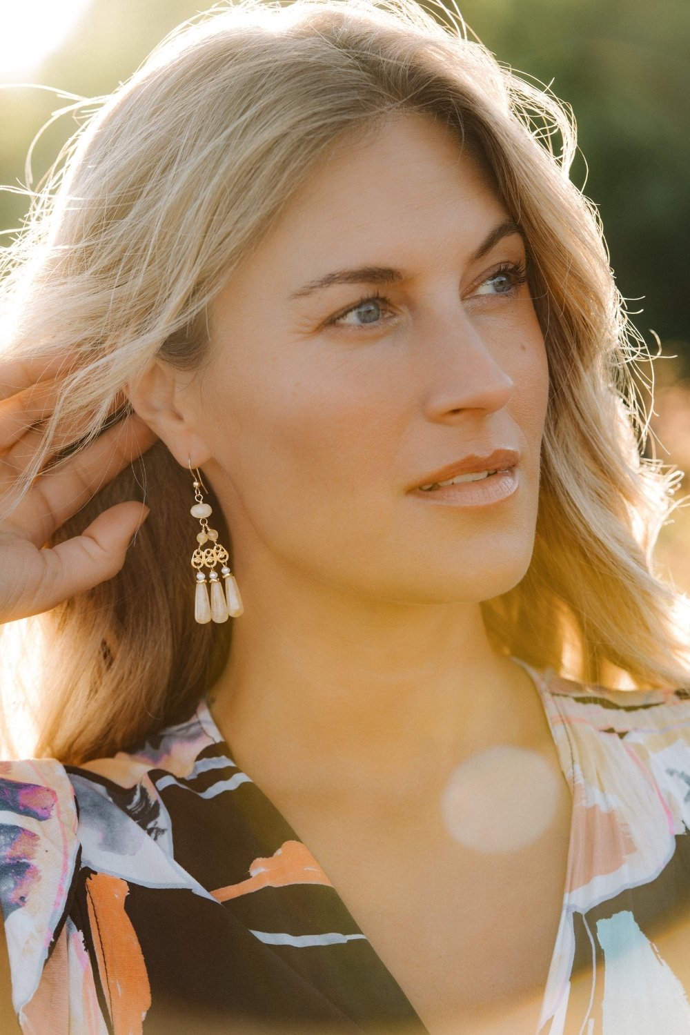 Woman with blonde hair and floral top outdoors wearing the buttercup chandelier earrings