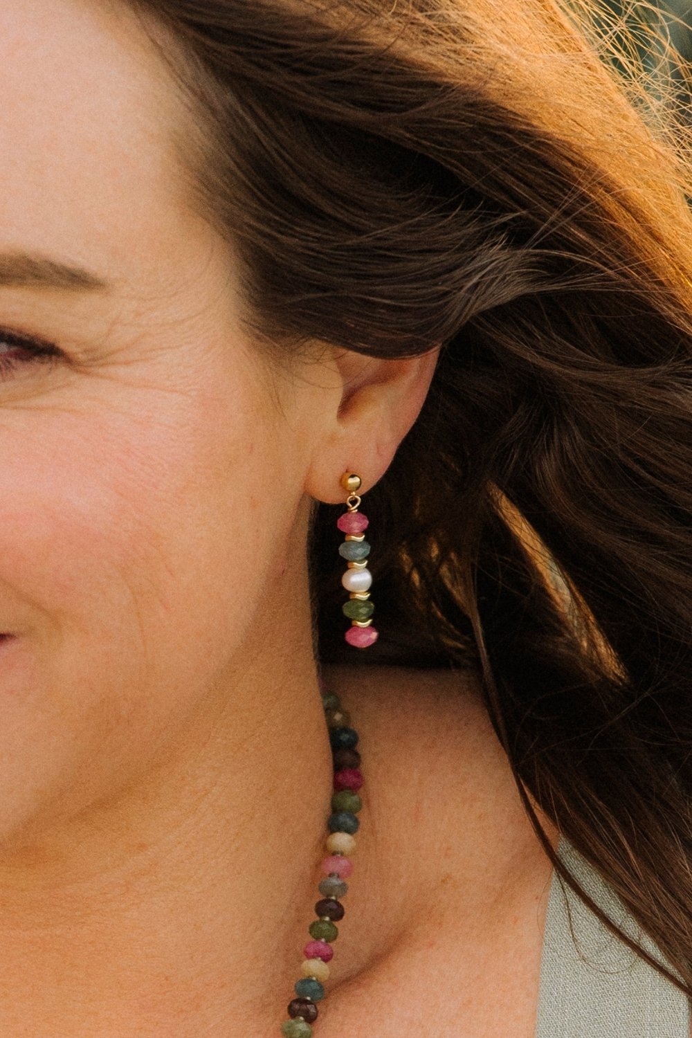 Close-up of a woman wearing colorful Catalina beaded earrings with hair blowing in the wind.