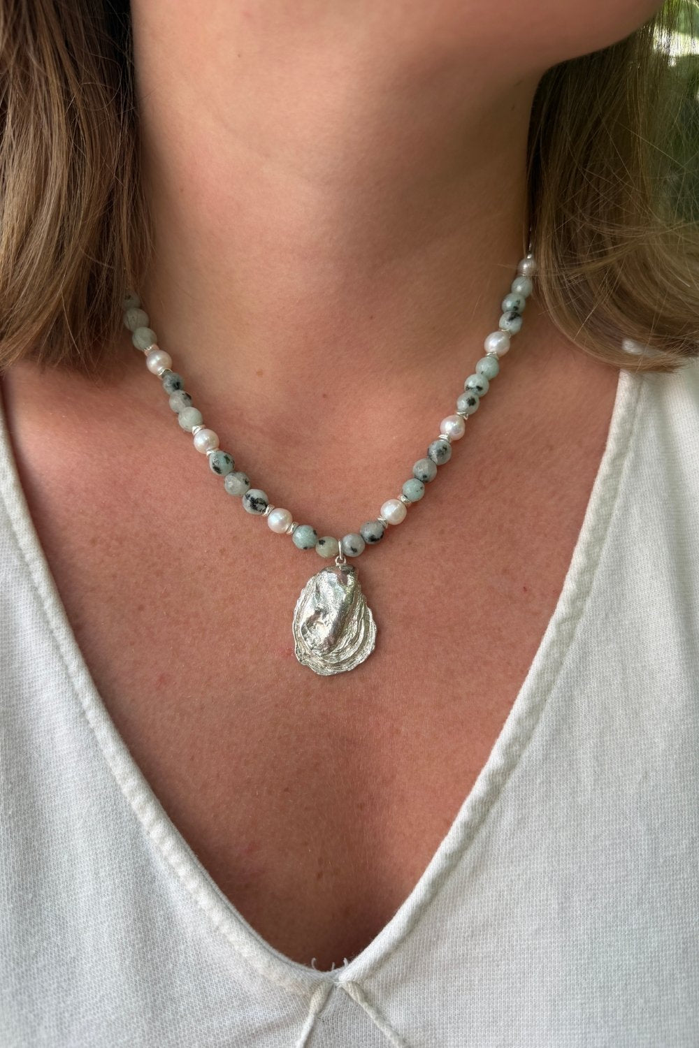 Creekside Oyster Necklace with an oyster pendant worn by a person in a white top