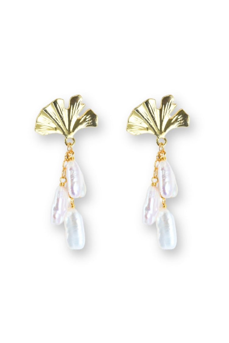 Gold earrings with gingko leaf shaped tops and teardrop-shaped pearls on a white background