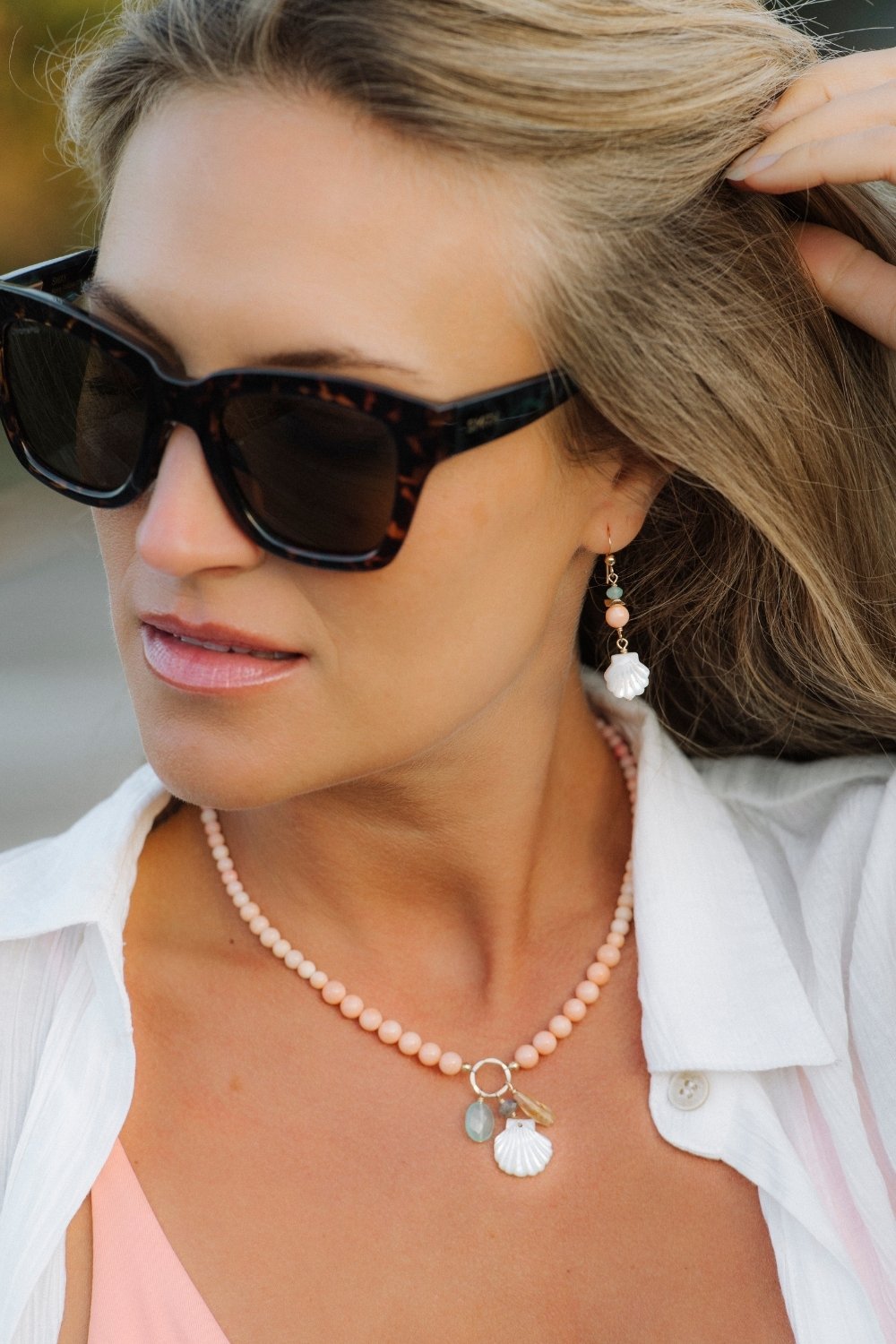 Woman wearing sunglasses and a matching golden hour necklace and earrings set