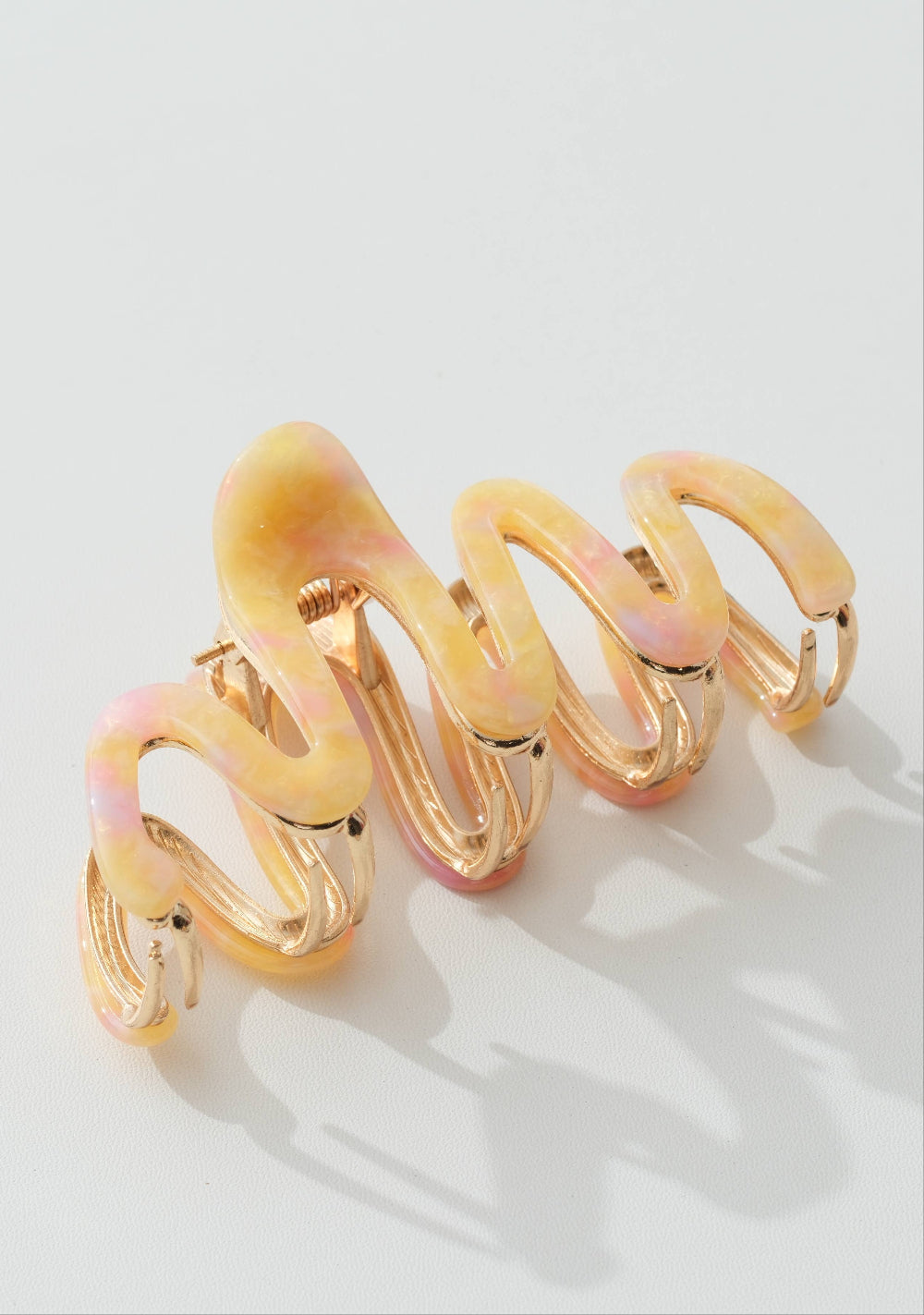 Yellow hair clip with pink accents on a white background