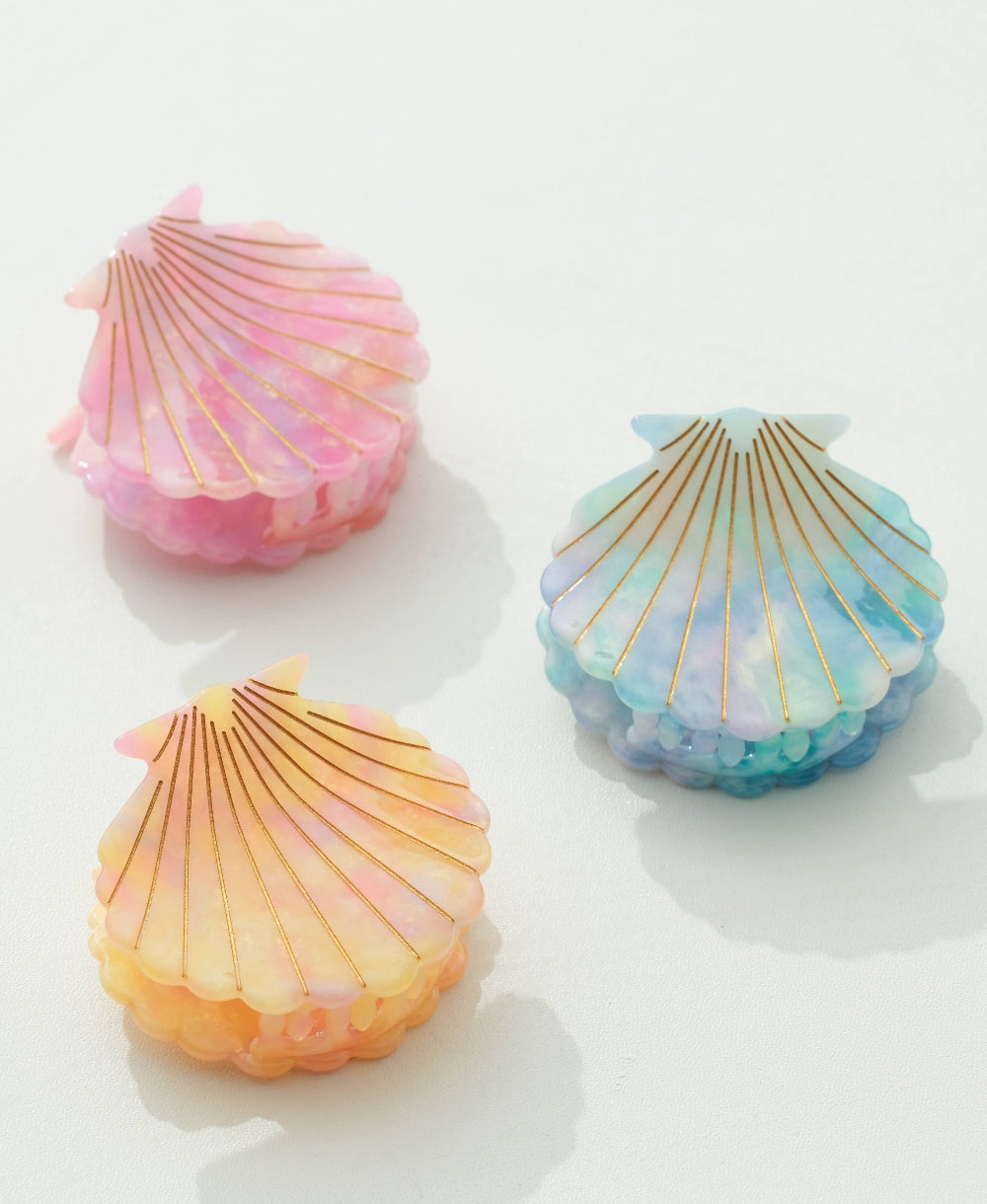 Three colorful shell-shaped hair clips on a white background