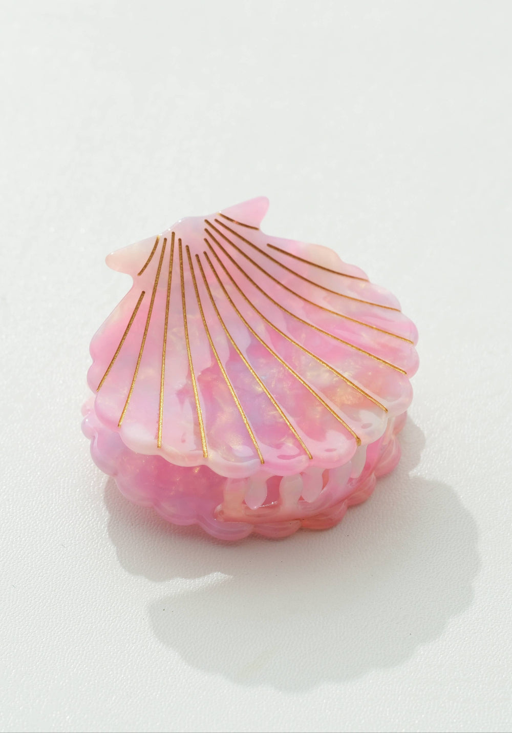 Pink shell-shaped claw clip with gold accents on a white background