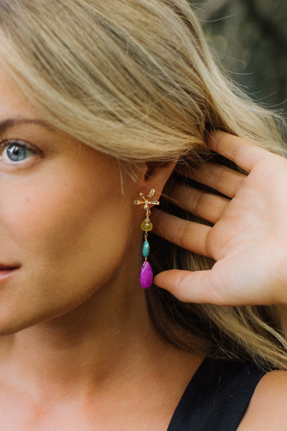 Close-up of a woman wearing colorful Lantana earrings with a blurred background