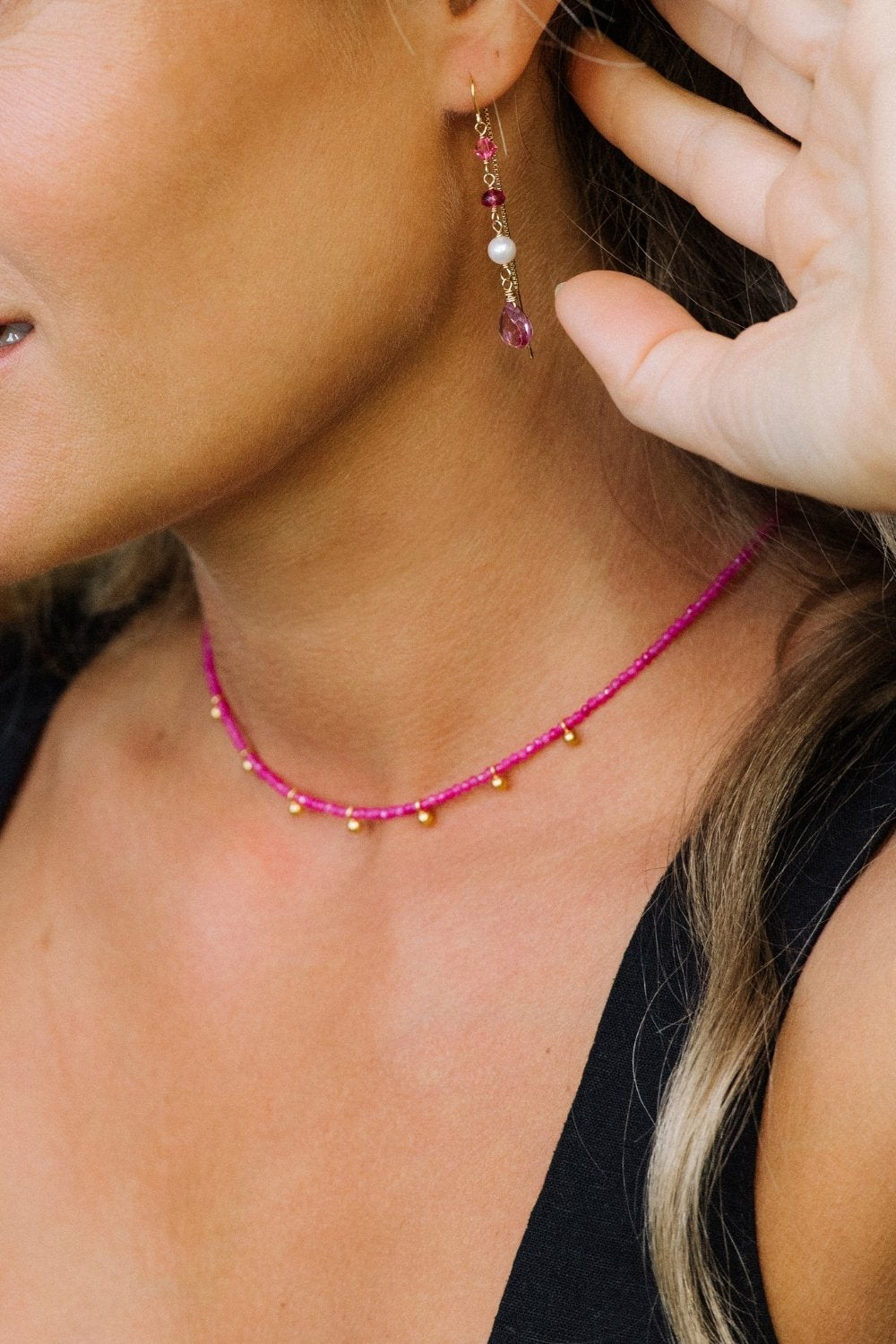 Close-up of a person wearing pink paloma beaded earrings and a matching pink paradise necklace.