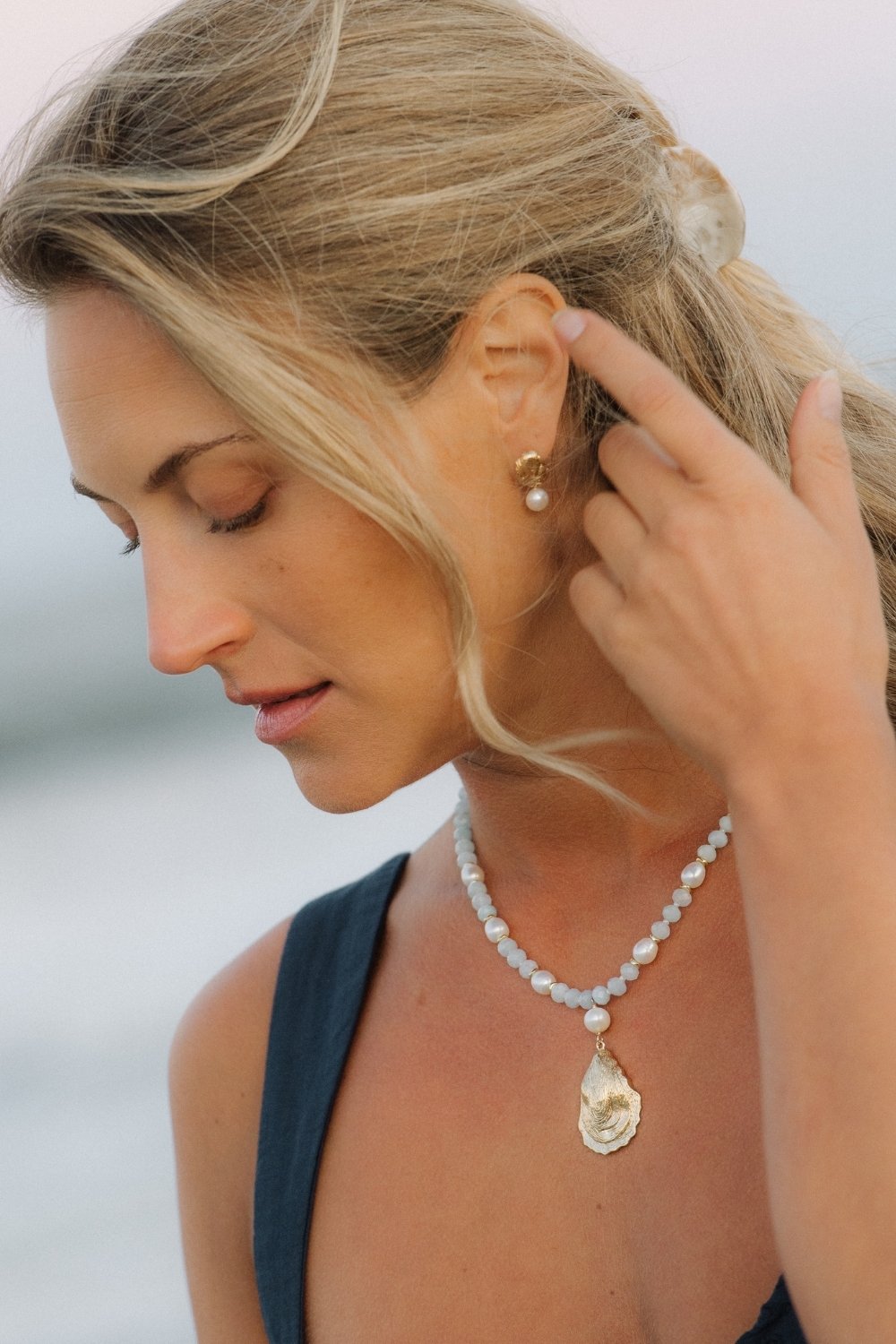 Woman adjusting a capers earring with a blurred background
