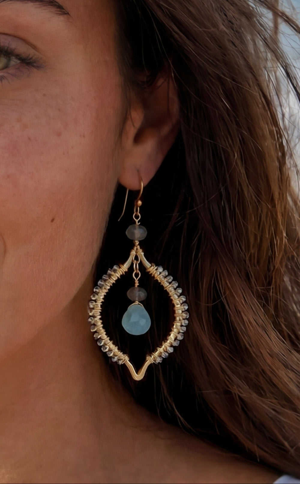 Woman on a beach wearing earrings with a scenic background
