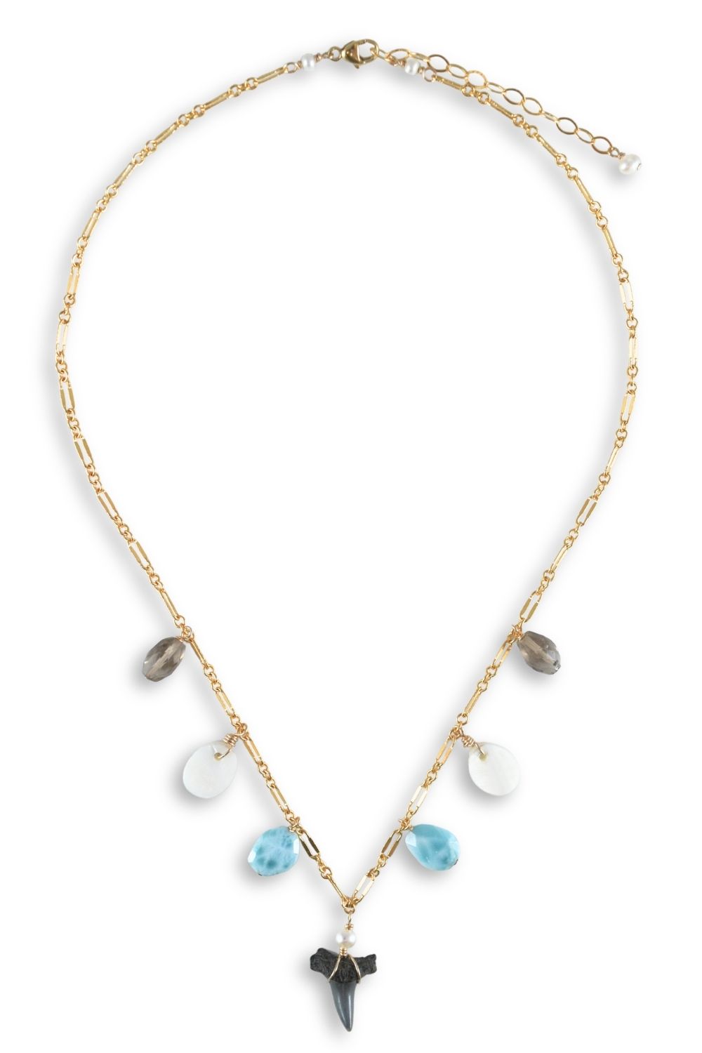 A gold chain necklace featuring a shark tooth pendant and dangling disc-shaped beads in light blue, white, and gray, displayed on a clean white background.