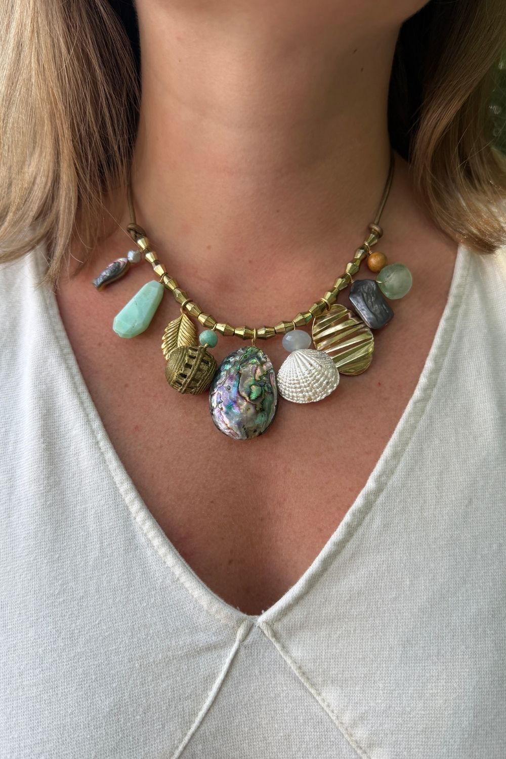 Necklace with various beads and stones worn by a person on a white background