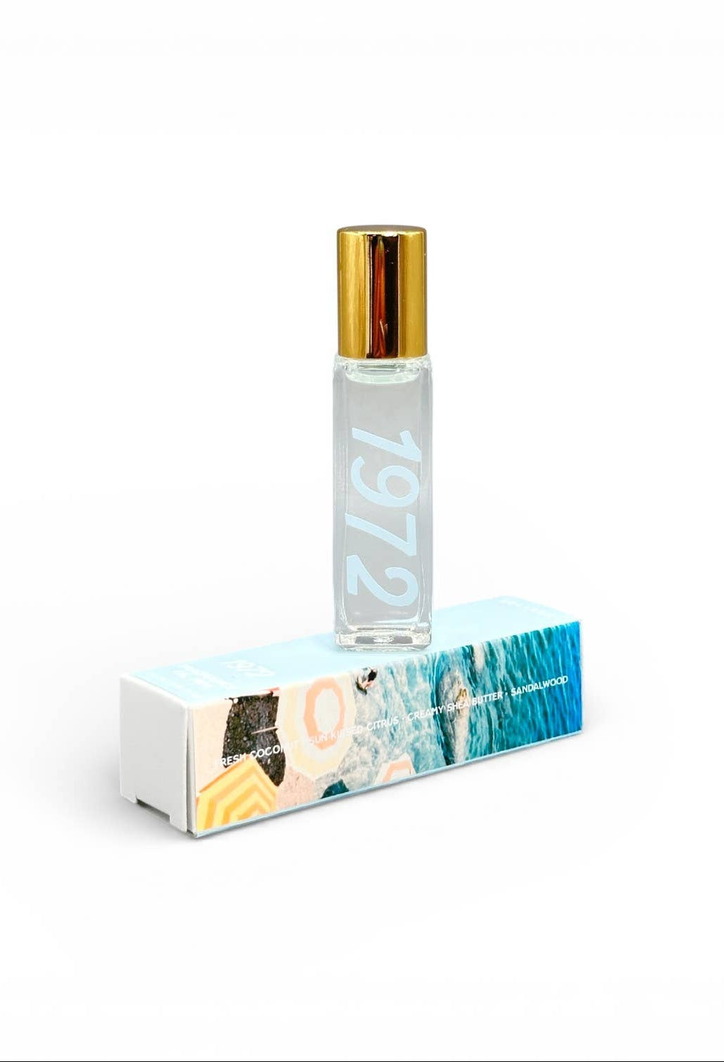 Roll-on perfume bottle with a gold cap and '1972' text, placed on a box with a scenic design.
