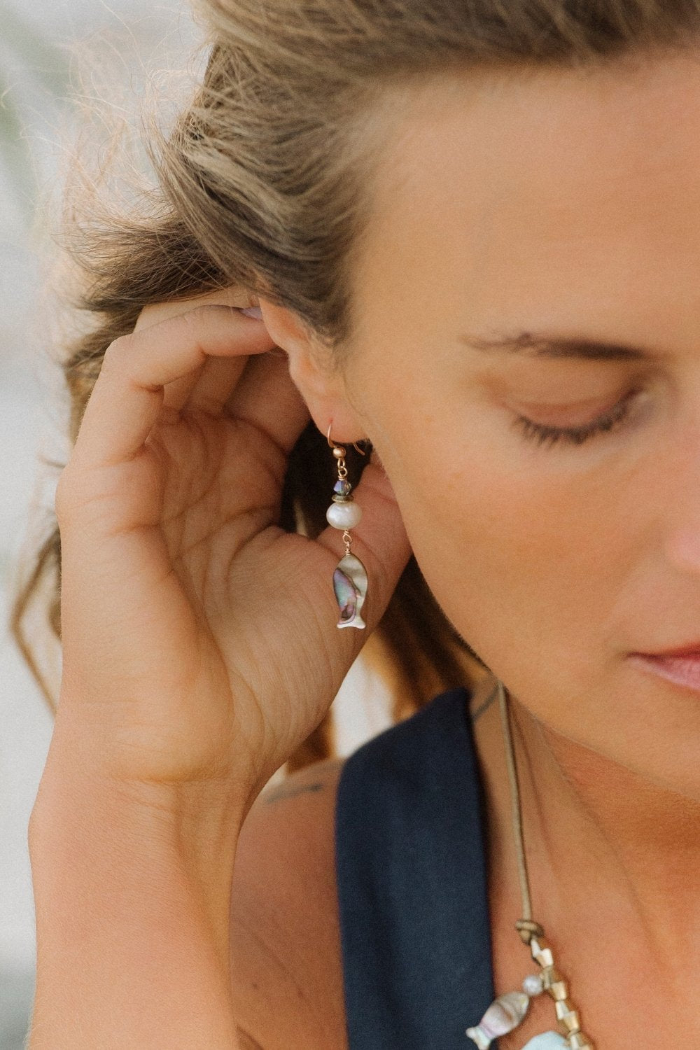 Close-up of a woman wearing abalone reef fish earrings with a blurred background