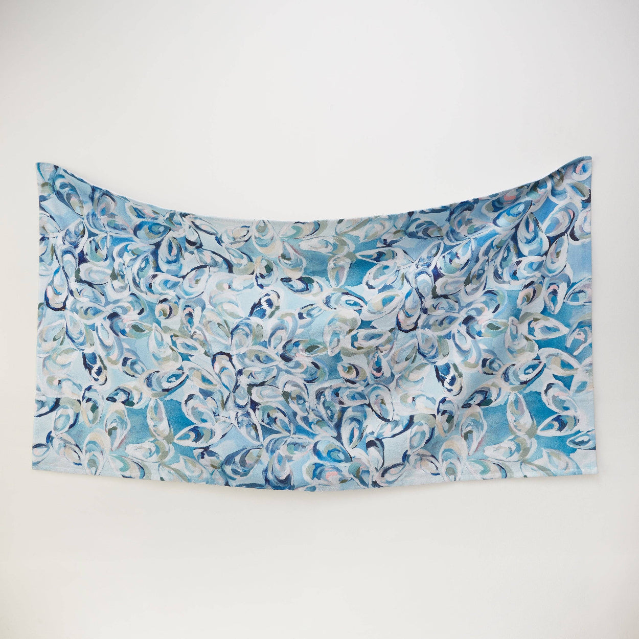 Blue and white oyster shell patterned beach towel on a white background
