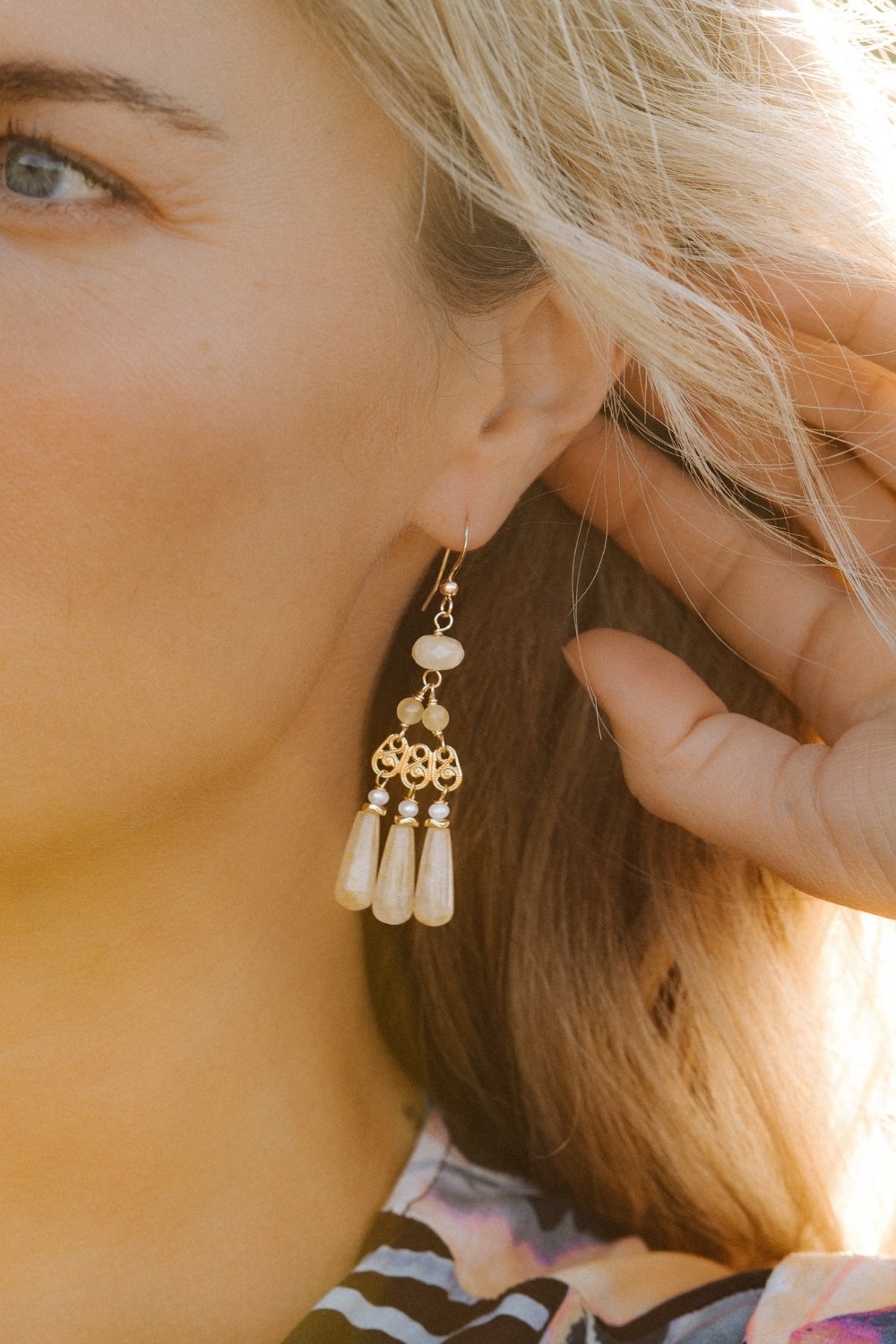 Close-up of a woman wearing a buttercup chandelier earring with yellow beads.