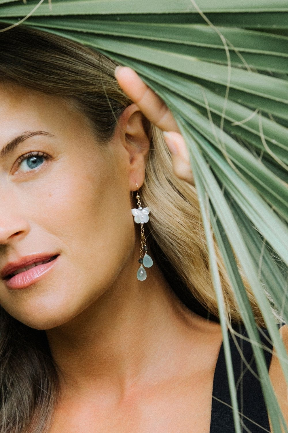 Woman wearing butterfly bloom earrings with a plant in the background