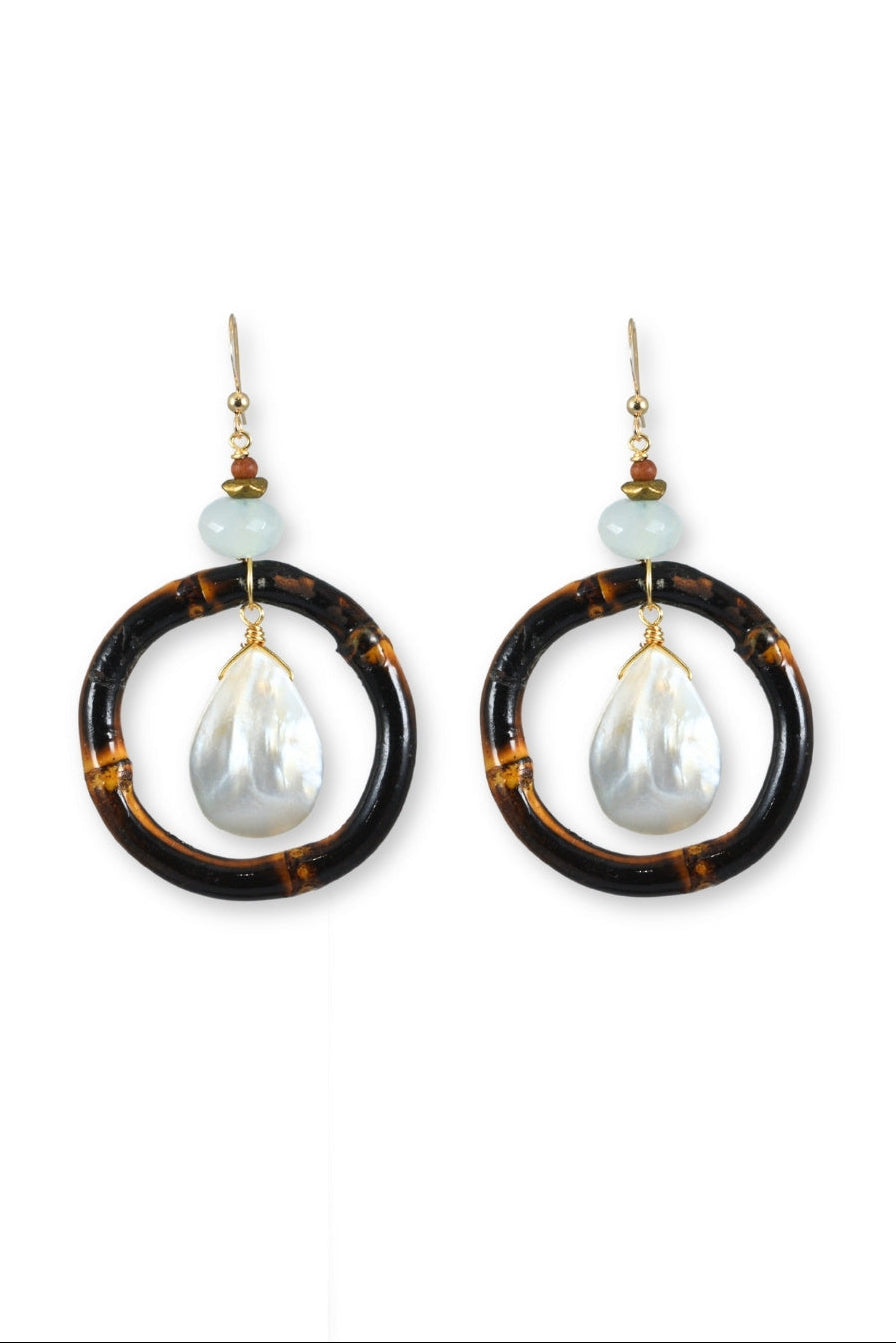 Pair of earrings with wood hoop and pearl drop design on a white background