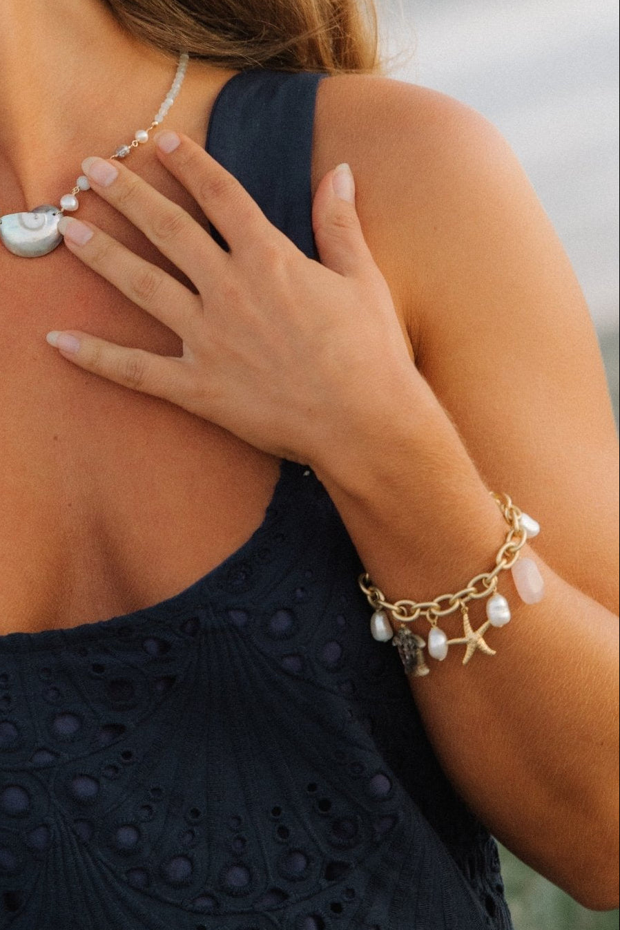 Woman wearing a coastal charm bracelet with a blurred natural background