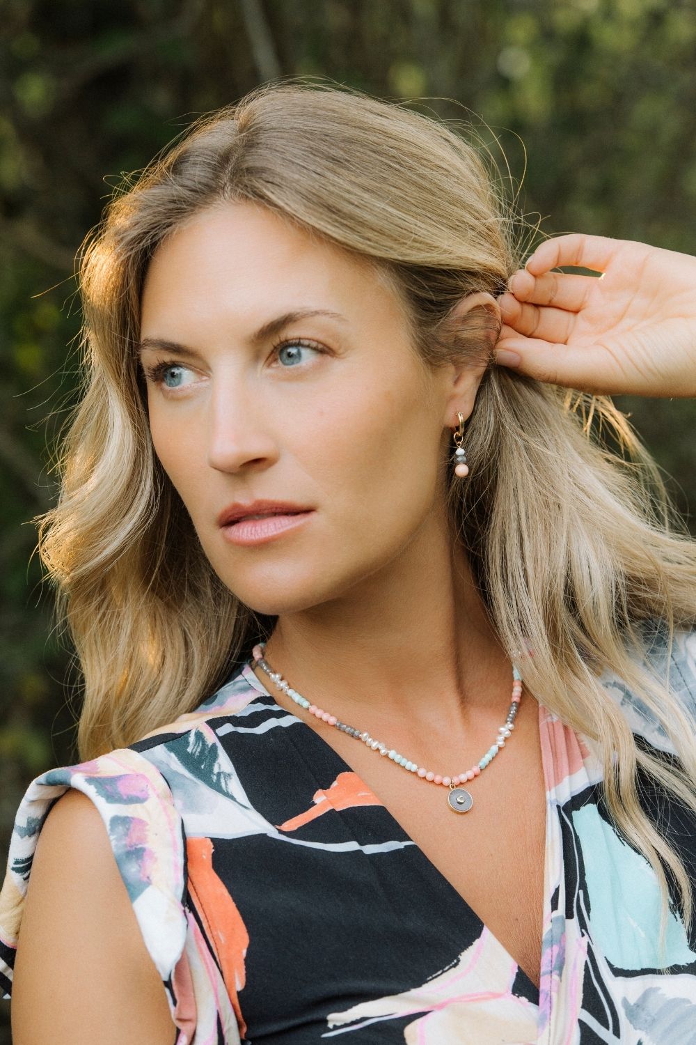 Woman with blonde hair wearing coral cove necklace and earring charm