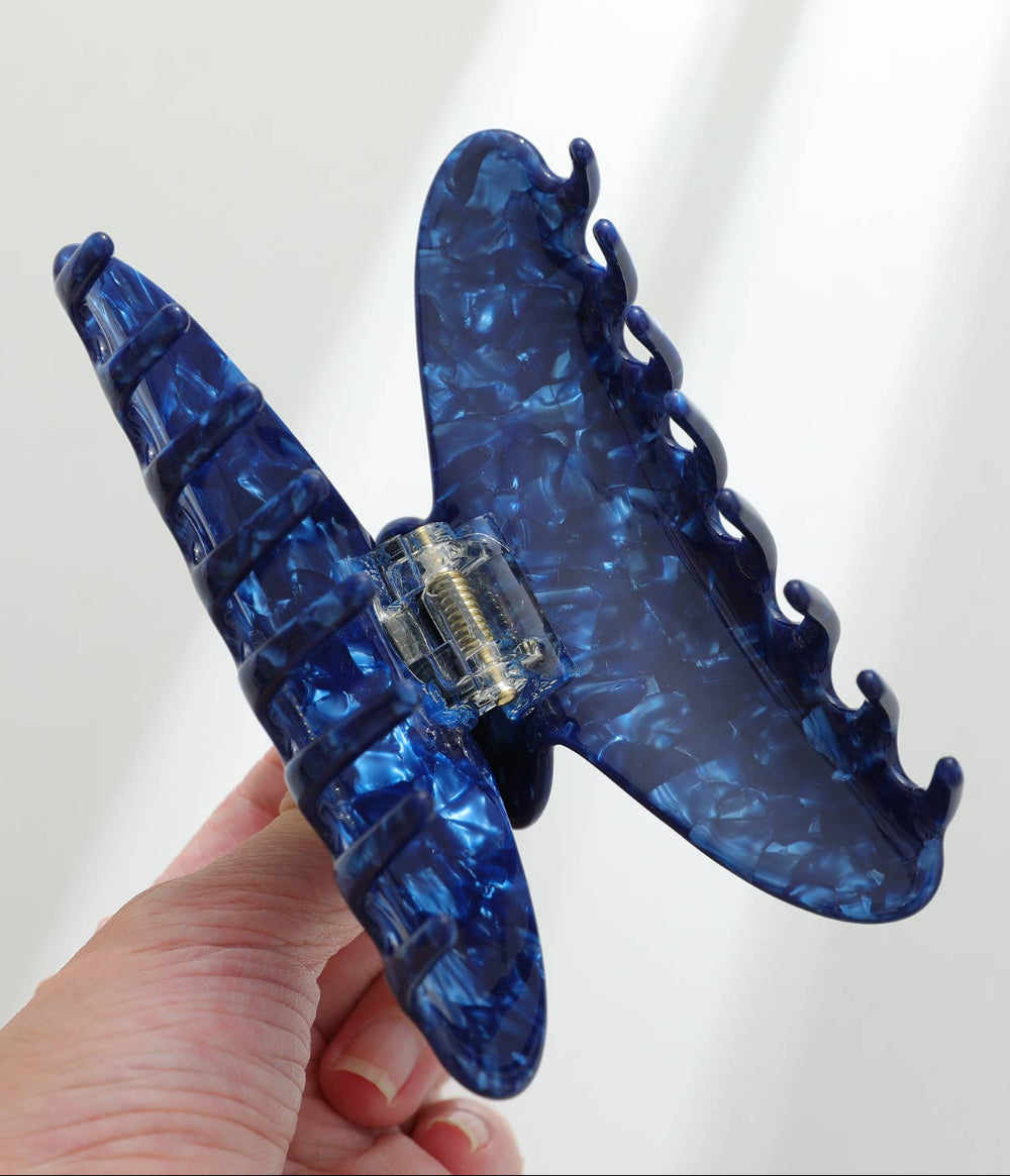 Blue textured hair clip held by a hand against a white background