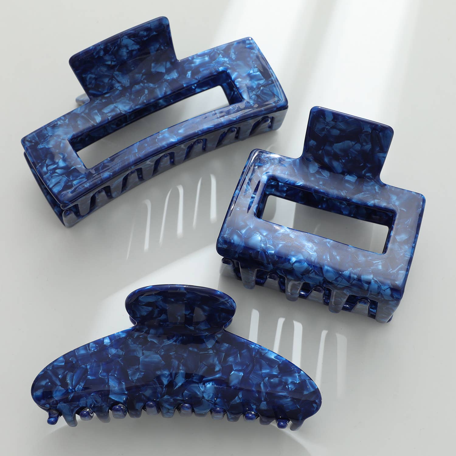 Three blue marbled hair claws on a white background