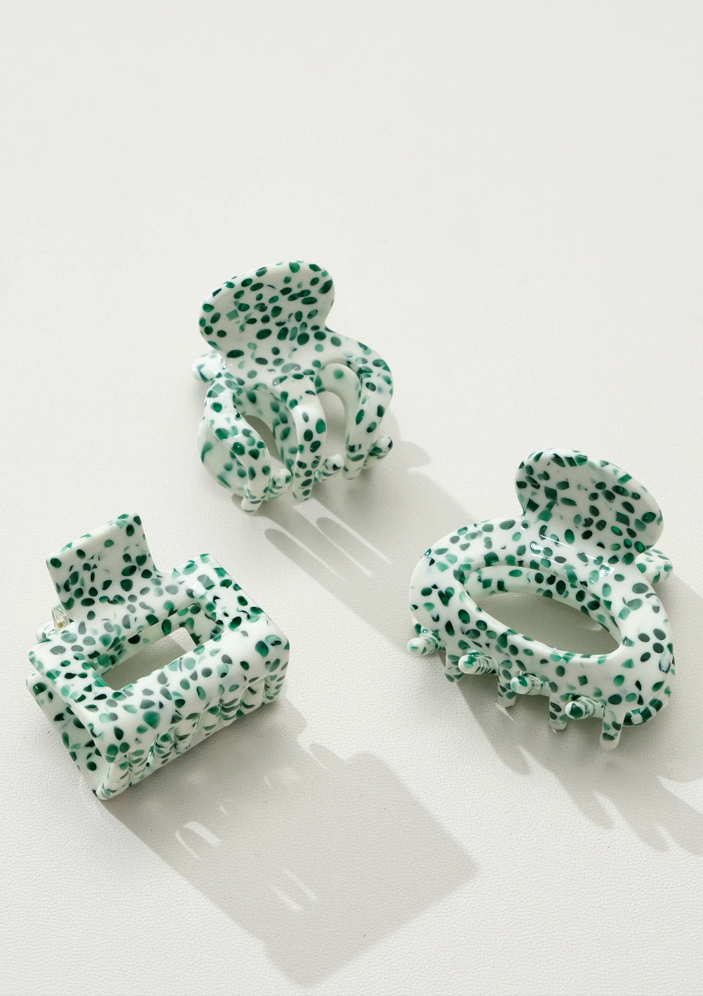 Set of green and white patterned hair clips on a white background