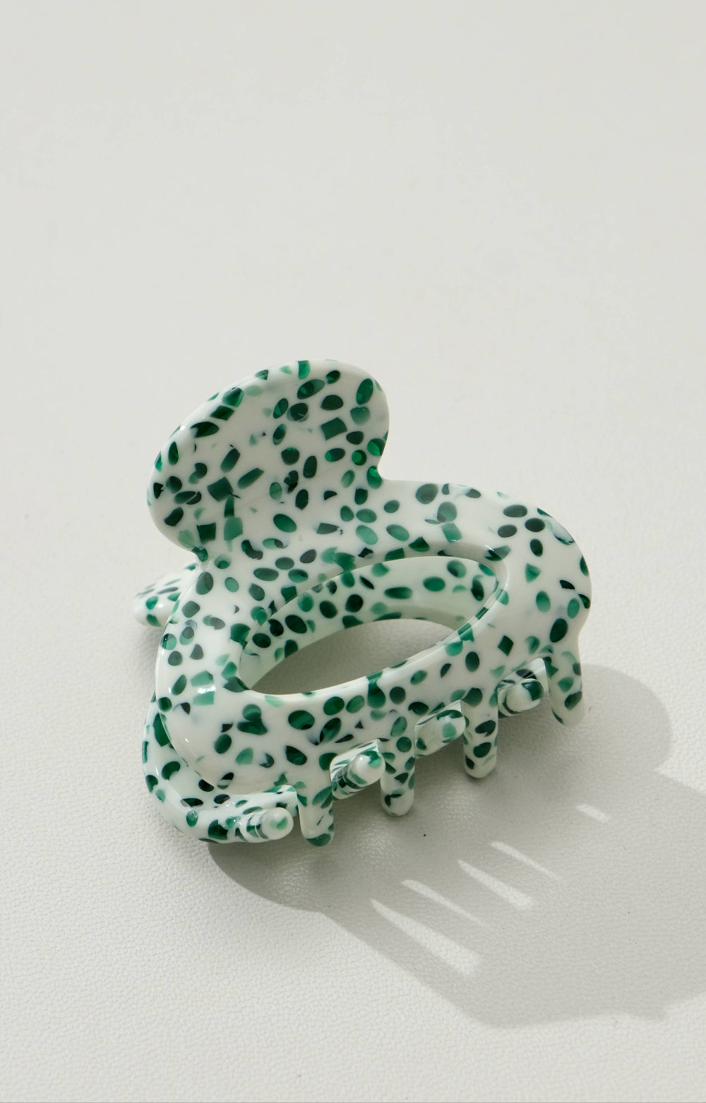 Green and white spotted hair clip on a light gray background