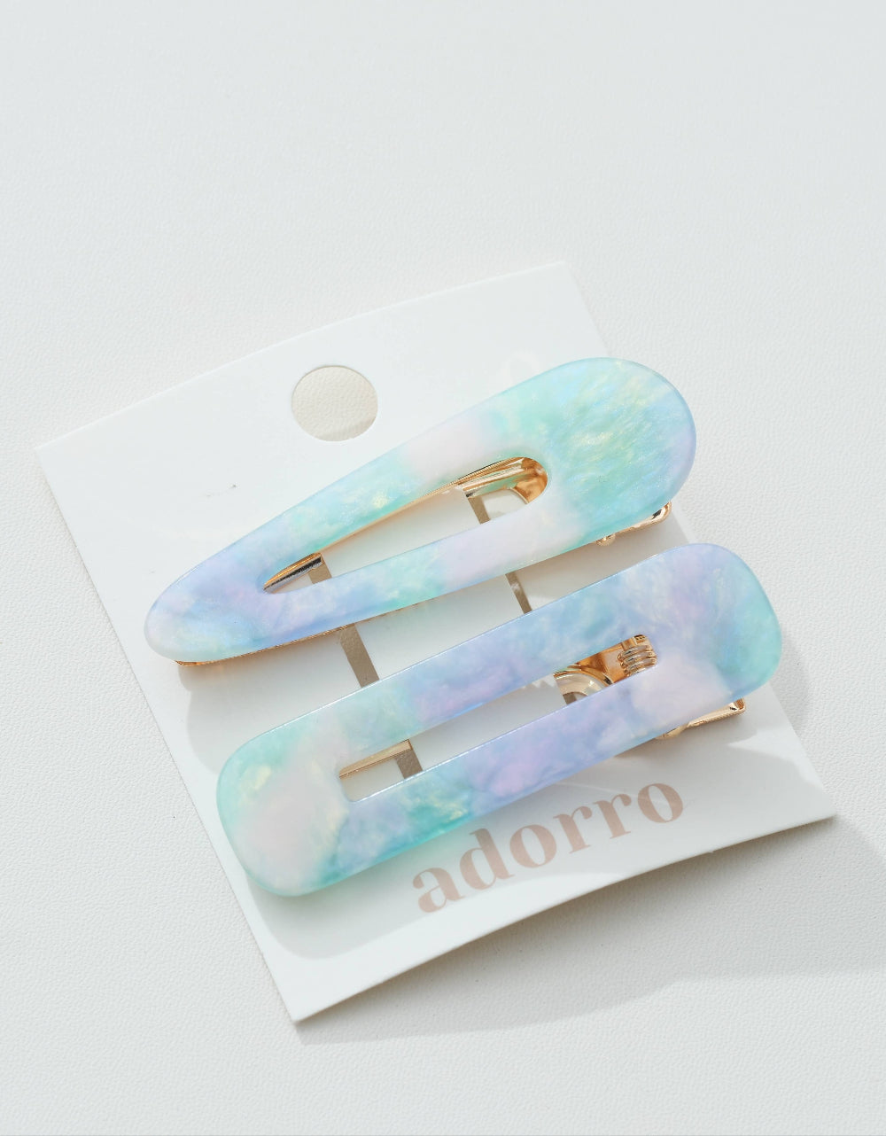 Two watercolor hair clips on a card with 'adorro' branding on a white background