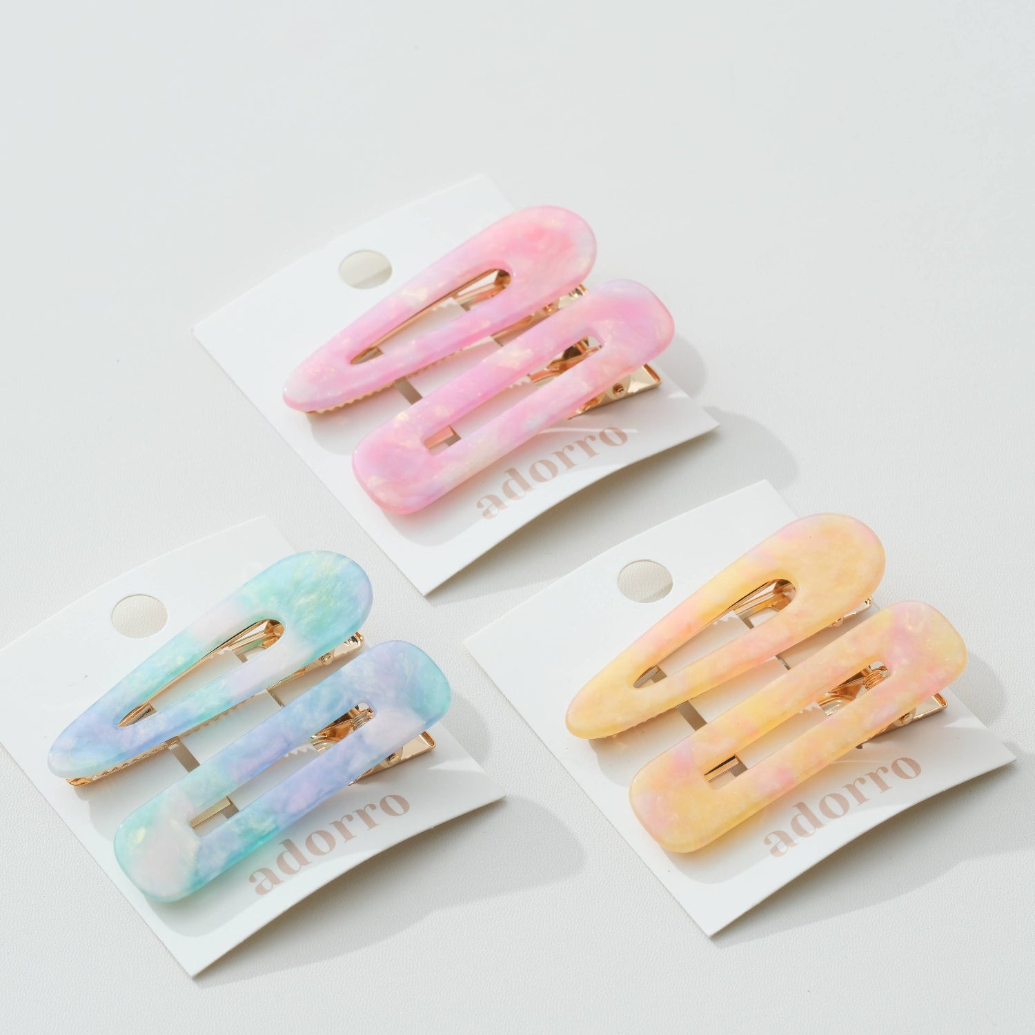 Set of pastel-colored hair clips on white cards with 'adorro' branding.