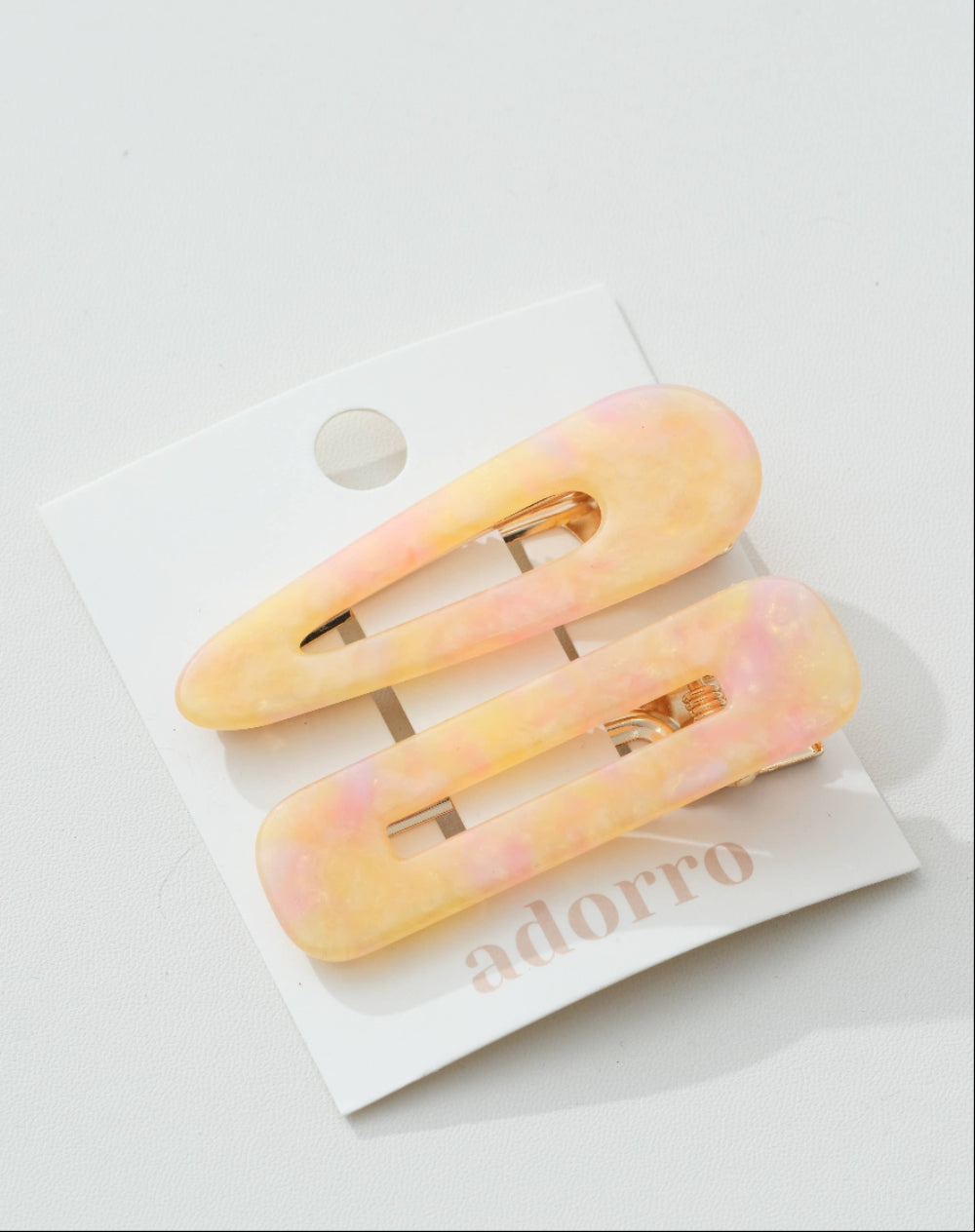 Two pink and yellow hair clips on a white card with 'adorro' branding.