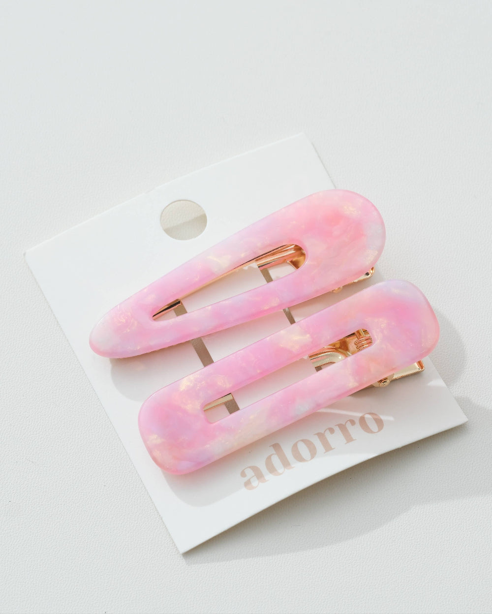 Two pink hair clips on a white card with 'adorro' branding.