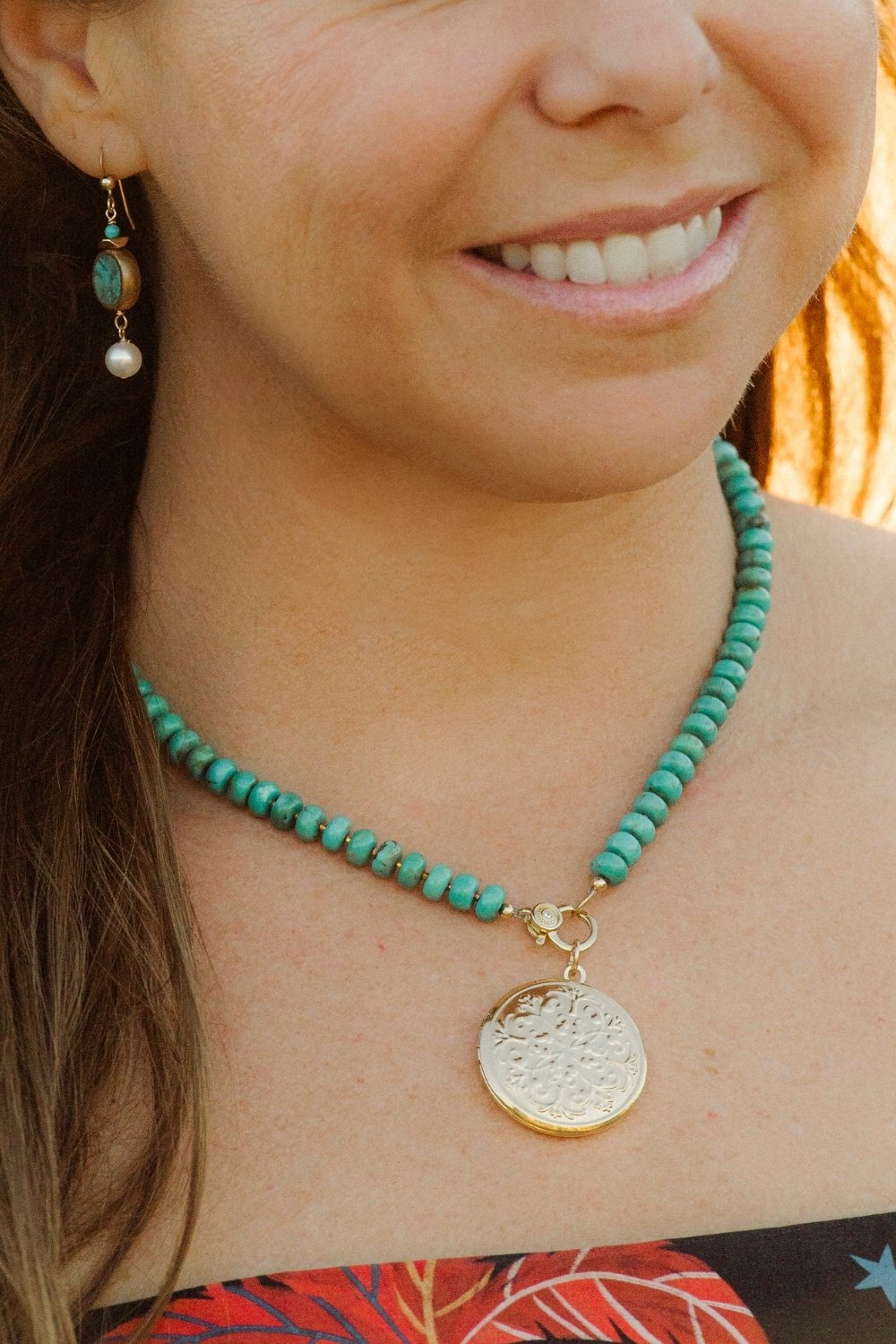 Close-up of a person wearing a turquoise beaded necklace with a gold locket charm.