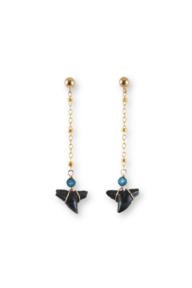 Pair of earrings with black shark teeth on gold chains against a white background