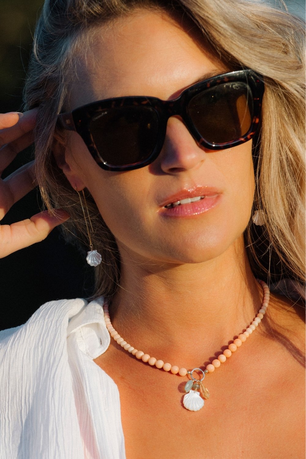 Woman wearing golden hour necklace and scallop shell threaders with a blurred background