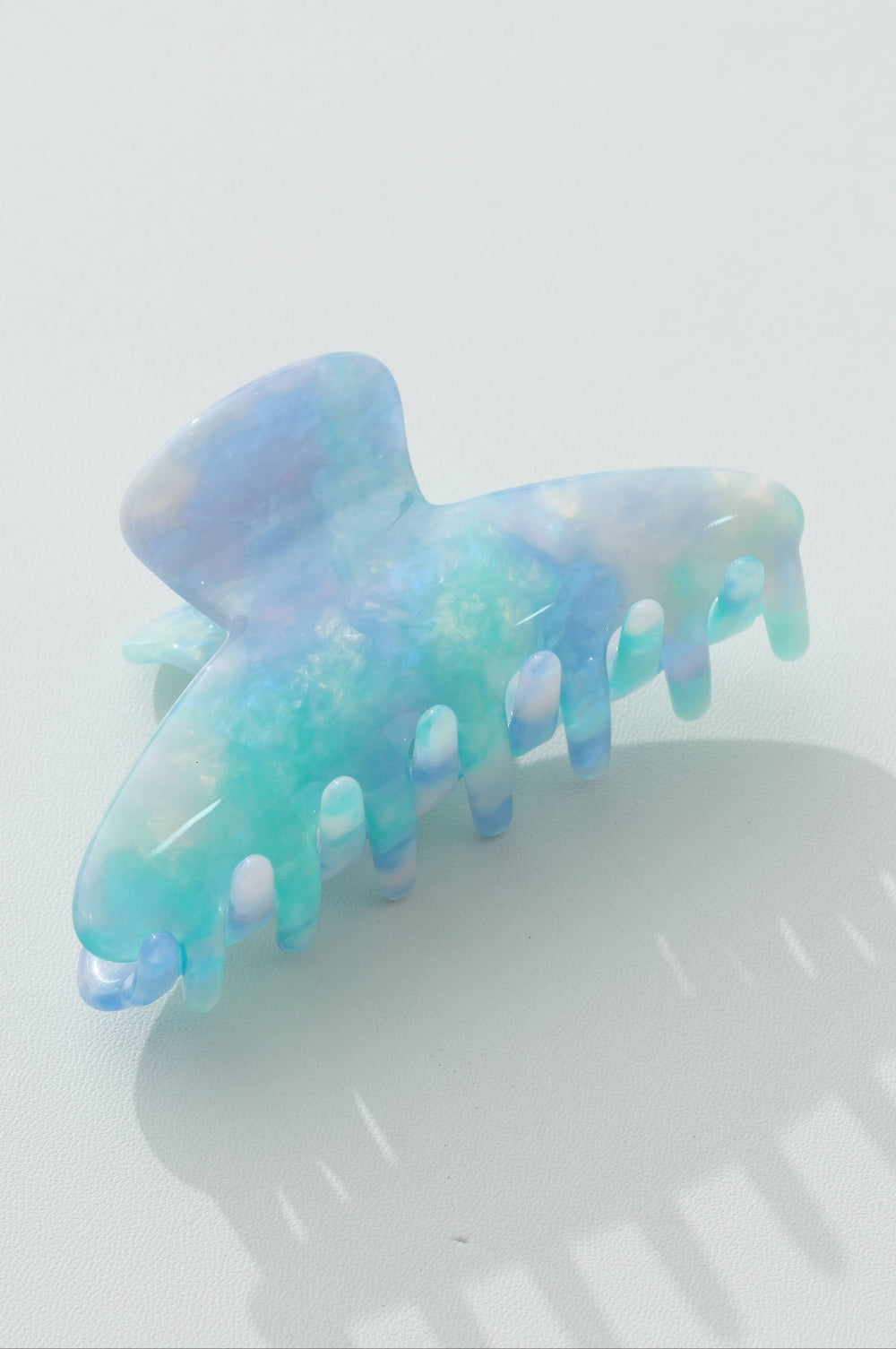 Opaline blue and green hair clip on a light gray background
