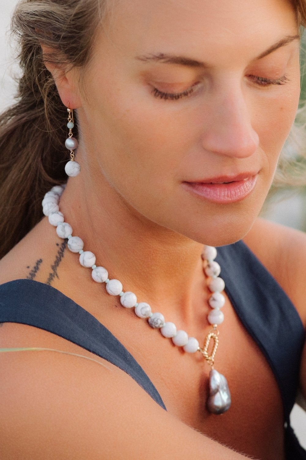 Woman wearing a seamist howlite necklace and earrings outdoors