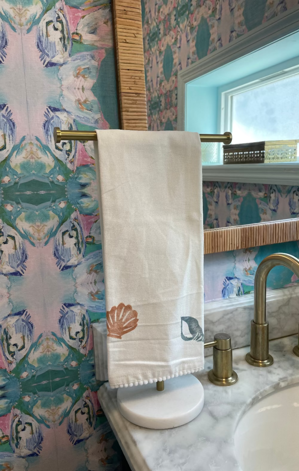 Linen tea towel with shell motifs folded on a stand in a bathroom