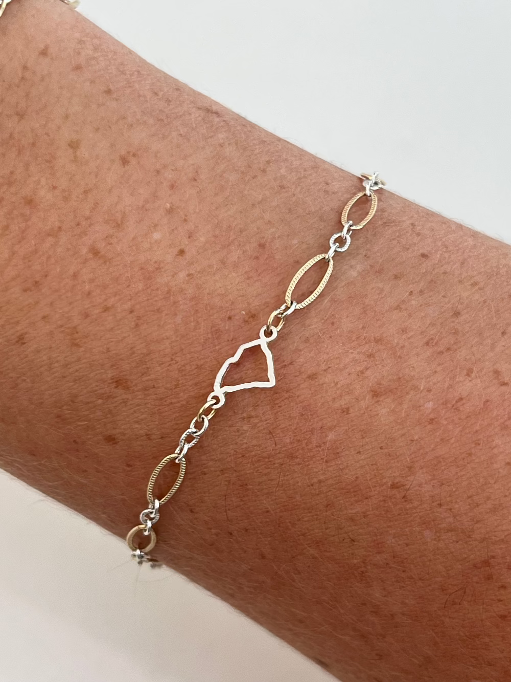 Gold bracelet on a wrist with a plain background