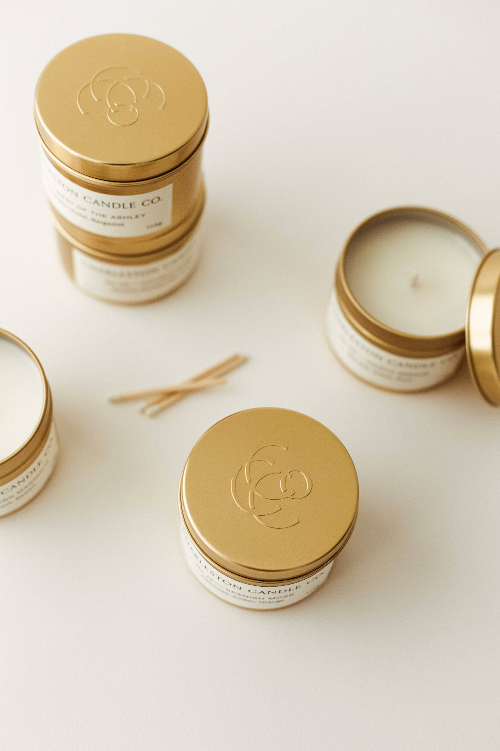 Gold-lidded candles with visible branding on a white surface