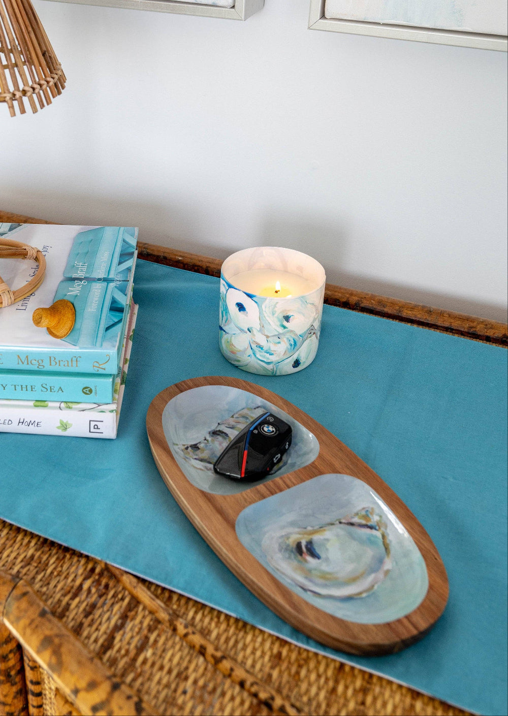 Decorative table setting with books, a candle, and a tray on a blue surface.
