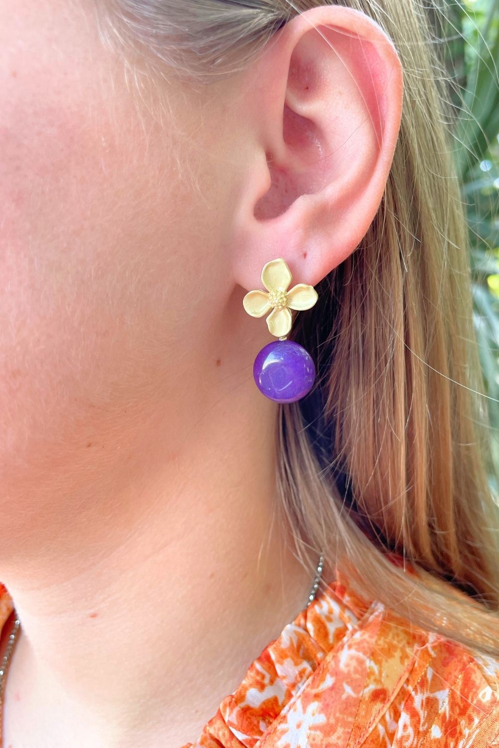 Gold enamel dogwood flower-shaped earrings with purple jade beads on model